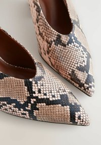 Spitze High Heels aus Kunstschlangenleder mit einem beige-schwarzen Muster. Glatte Textur mit glänzendem Finish und ausgeschnittenem Design im Bereich des Spann.
