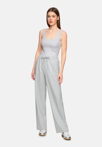 Light grey tank top paired with wide-leg, light grey plaid trousers featuring an elastic waistband and drawstring. Model wearing silver sneakers.