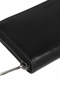 Portafoglio in pelle nera con una texture liscia, chiusura con zip tutto intorno e accessori in metallo. Presenta un marchio discreto e un design minimalista.