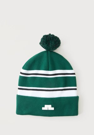 Bonnet en tricot vert avec des rayures horizontales blanches et noires, un pompon sur le dessus, et un petit logo blanc sur le bord.