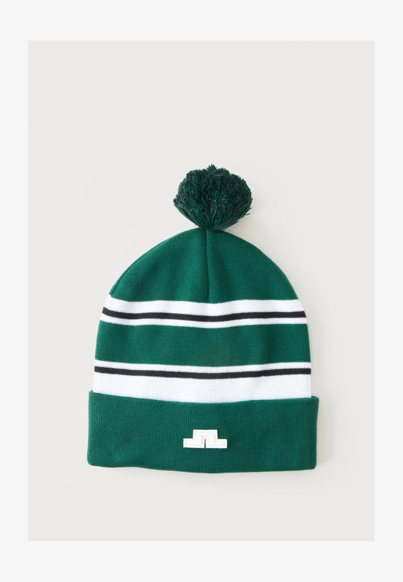 Bonnet en tricot vert avec des rayures horizontales blanches et noires, un pompon sur le dessus, et un petit logo blanc sur le bord.