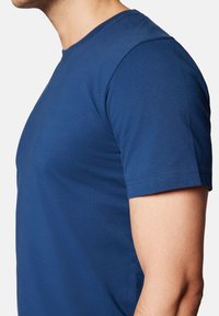 Niebieska koszulka z krótkim rękawem wykonana z gładkiego materiału bawełnianego, z klasycznym dekoltem w serek oraz dopasowanym krojem z subtelnymi detalami w szyciu.