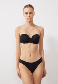 Musthave mustriba rinnahoidja pitsäärisega ja sobivad mustad bikiinipüksid. Sile tekstuur, vooderdatud tassid ja minimalistlik disain.