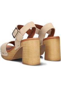 Beige suède sandalen met hak, voorzien van een brede blokhak, open teenontwerp, verstelbare enkelband en metalen studaccenten.