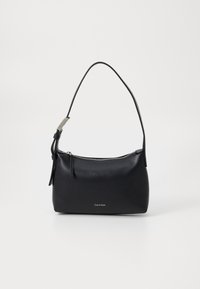 Sac à main en cuir noir avec une forme incurvée, fermeture éclair, et une bandoulière détachable. Présente un petit logo à l'avant et une surface texturée.
