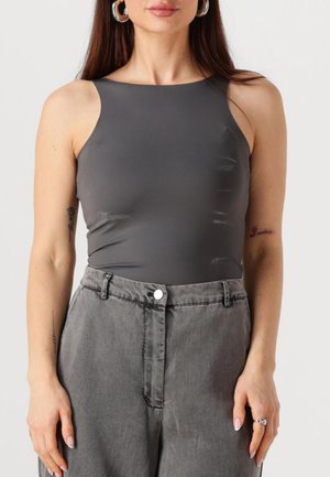 Body senza maniche grigio con una texture liscia, abbinato a pantaloni di jeans grigi a vita alta con chiusura a bottone e tasche laterali.