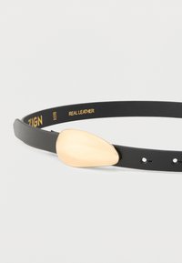 Mustast nahast rihm ebaühtlase, siledapinnalise kuldse sangaga, millel sees on kuldne tekst "ZIGN" ja "REAL LEATHER".