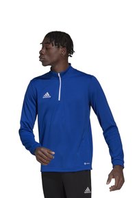 Blauwe sportieve zip-up top met lange mouwen, gemaakt van soepel stof, heeft een witte rits en een logo op de borst.