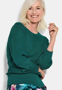 Grüner Strickpullover mit ribbeltem Halsausschnitt und Saum, einem strukturierten Muster und lässig geschnittenen Ärmeln.