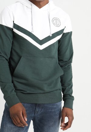 Sudadera verde oscuro con diseño de chevron blanco, bolsillo frontal, capucha con cordón y logo. Fabricada con un tejido suave y texturizado.