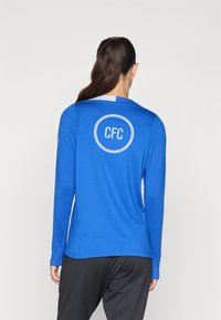 Long-sleeve blue training shirt with round neckline, featuring a white "CFC" logo on the back and a smooth, lightweight fabric texture.