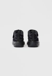 Baskets de sport noires avec une tige en synthétique, un col rembourré, une semelle en caoutchouc et des détails de marque signature à l'arrière et sur les côtés.