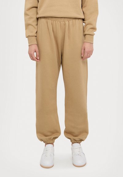 Beige sweatpants met een elastische tailleband en boorden, met een zachte textuur en een relaxte pasvorm. Draag ze met witte sneakers.