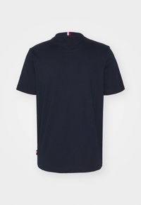 Camiseta de algodón color azul marino con mangas cortas y escote redondo. Presenta un detalle en rojo y blanco en la parte posterior del cuello.