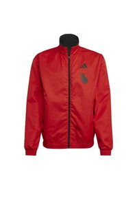 Veste coupe-vent rouge avec col noir, fermeture éclair intégrale, poignets et ourlet élastiques ; présente des accents de logo noirs à l'avant.