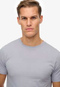 Lys grå kortærmet t-shirt i en blød, glat bomuldsblanding. Har en klassisk rund halsudskæring og en tætsiddende silhuet.