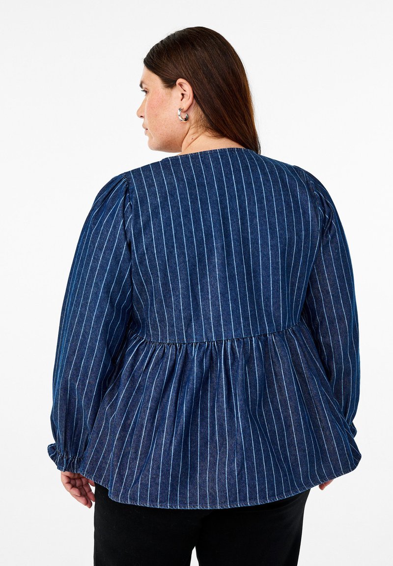 Mörk denimblus med vertikala blå ränder, puffärmar och ett insamlat midjebälte. Bakre halsringningen är rundad och har en flödande silhuett.