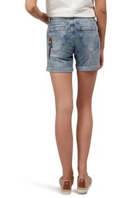 Jasnoniebieskie szorty jeansowe z podwiniętym brzegiem i haftowanym wzorem papugi na tylnej kieszeni. Postarzany wygląd i fason z pięcioma kieszeniami.