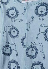 Svetlo modri bodysuit z motivom levov, ki ima gumbne zaponke in mehak material. Oblikovanje vključuje igrive obraze levov z grivami.