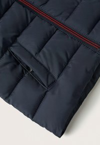 Puffjacka i marinblått med en kviltad design, en horisontell röd dragkedja och en ficka med dragkedja och en mjuk textur.