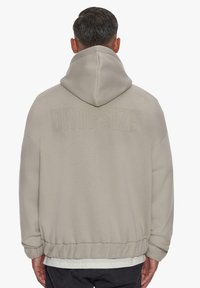 Beige hooded sweatshirt with a relaxed fit, featuring a ribbed hem and a faint "DROPSIZE" text on the back. Soft fabric texture.