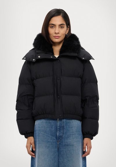 Jachetă puffer neagră cu guler din blană sintetică, având un design scurt, închidere cu capse și fermoar, textură matlasată și manșete elastice.