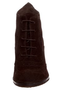 Stivale alla caviglia in suede marrone con punta appuntita, lacci davanti e cuciture decorative lungo i bordi. Superficie liscia.