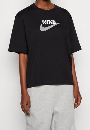 T-shirt en coton noir avec un col rond et une coupe oversize. Présente un logo Nike blanc et un motif swoosh aux tons argentés et violets.