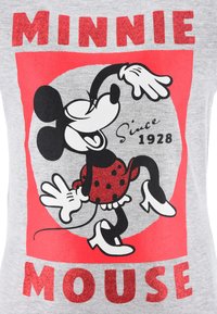T-shirt gris avec un graphisme imprimé de Minnie Mouse dans une robe rouge à pois noirs, entourée de noir, et le texte "MINNIE MOUSE."
