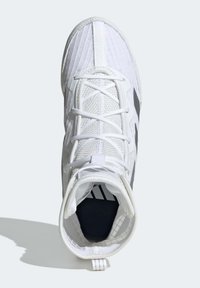 Valkoinen urheilukengän päällinen on teksturoitu, valmistettu synteettisistä materiaaleista, varvastila on tilava ja sivussa on musta logo. Nauhat paikallaan.