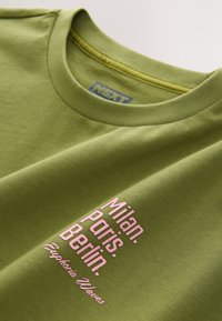 Olivgroen katoenen T-shirt met een ronde hals. Voorzien van roze bedrukt tekst met de woorden "Milaan. Parijs. Berlijn. Euphoria Values."