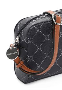 Sac à main noir à motifs avec bandoulière marron réglable, fermeture éclair argentée et pendentif rond en argent marqué Tamaris.