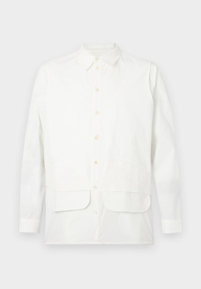 Camisa blanca de botones hecha de algodón, con un collar clásico, dos bolsillos frontales y un dobladillo recto. Textura suave, diseño minimalista.