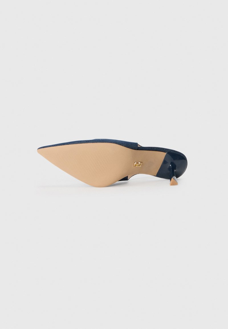 Mule de couleur marine à bout pointu au design épuré, avec une finition brillante et un talon effilé. La semelle est beige avec des détails texturés.