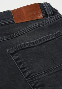 Gesäßtasche und Leder-Label auf schwarzen Jeans mit "bugatti" und "AUTHENTIC DENIM" geprägt.