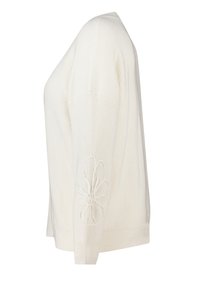 Pull en maille blanc avec un col en V, texture côtelée et un détail de broderie florale sur la manche gauche.