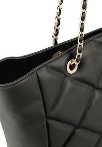 Zwarte leren handtas met een gestikte ontwerp, metalen oogje en kettingriem met leren accenten, die een strakke en gestructureerde vorm toont.