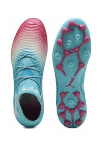 Botas de fútbol con un degradado en aqua y rosa, con parte superior texturizada, cordones y tacos morados sobre una suela azul. Presenta el logo de Puma en el costado.