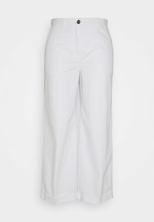 Un pantalon large taille haute blanc avec une fermeture à bouton et des ourlets repliés, suspendu sur un fond blanc.