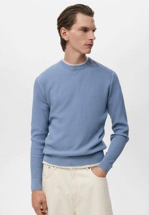 Suéter de canalé azul claro con cuello redondo, mangas largas y dobladillo ajustado, combinado con pantalones de color claro. Tejido suave y texturizado.