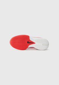 Nike athletic shoe outsole featuring a textured red rubber pattern, white midsole, and a black logo. Smooth surface with a flexible design.