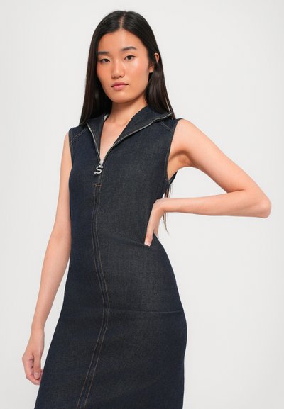 Denim brezrokavnik z zadrgo spredaj, temno modre barve, prilegajoče se zasnove in detajli v oranžni barvi, z bočnimi žepi.