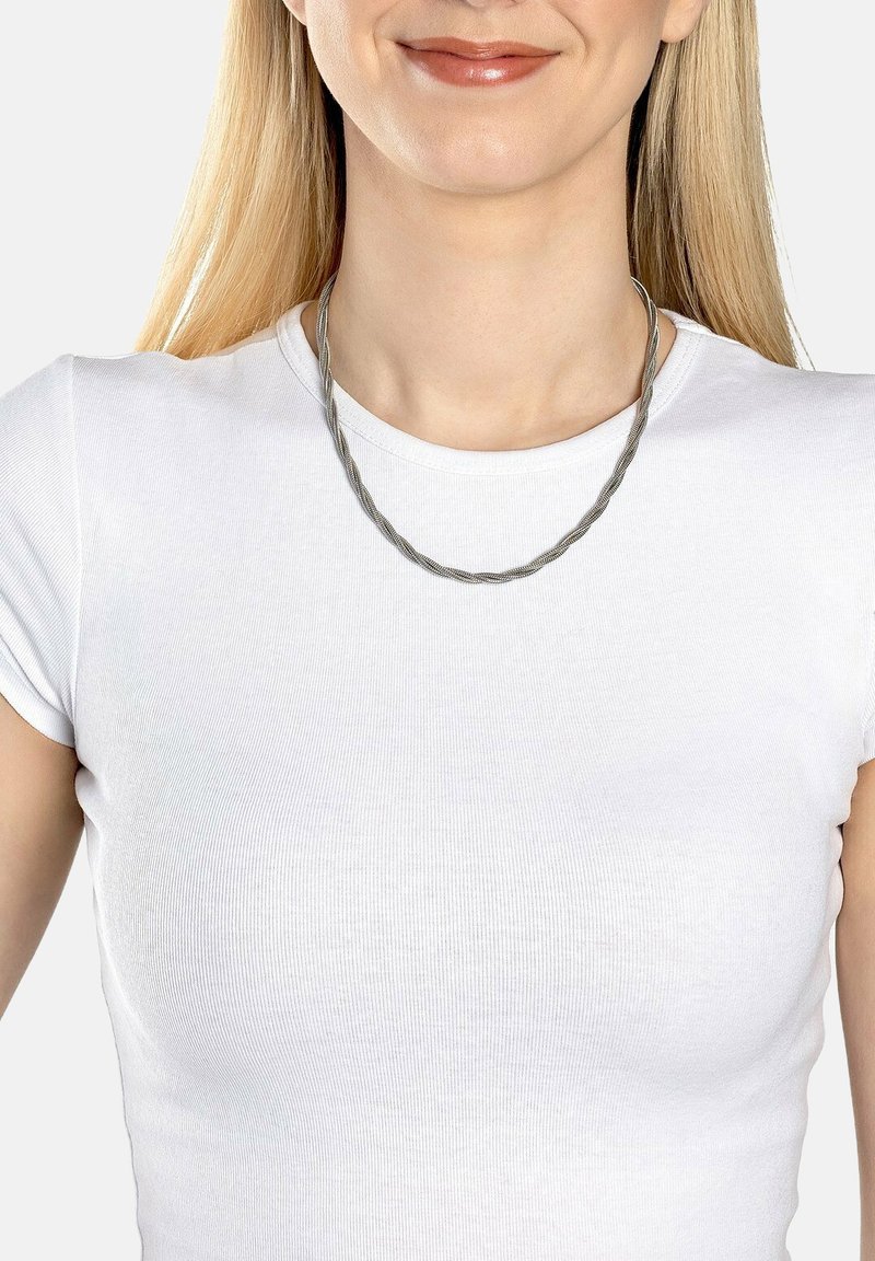 Grå metal halskæde med et snoet design, der ligger på en hvid t-shirt. Glat overflade, let og mellemlangt.