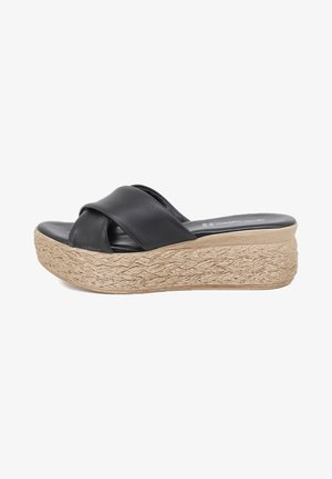 Sandali platform in pelle nera con cinturini incrociati e suola in stile juta intrecciata. La suola è spessa e testurizzata, migliorando la presa e lo stile.