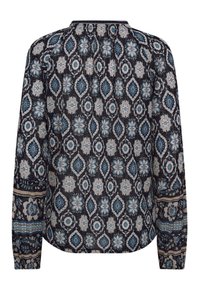 Langslippende blouse in marineblauwe stof met intrigerende bloemen- en geometrische patronen in blauw, crème en zwart. Knopenlijst aan de achterkant.