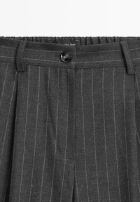 Pantalon gris foncé à fines rayures avec fermeture à bouton, passants de ceinture et taille partiellement élastique.