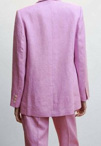 Różowa marynarka z lnu o dopasowanym kroju, z pojedynczym rozcięciem i guzikami na mankietach. Gładka tekstura i lekko oversize'owy fason.