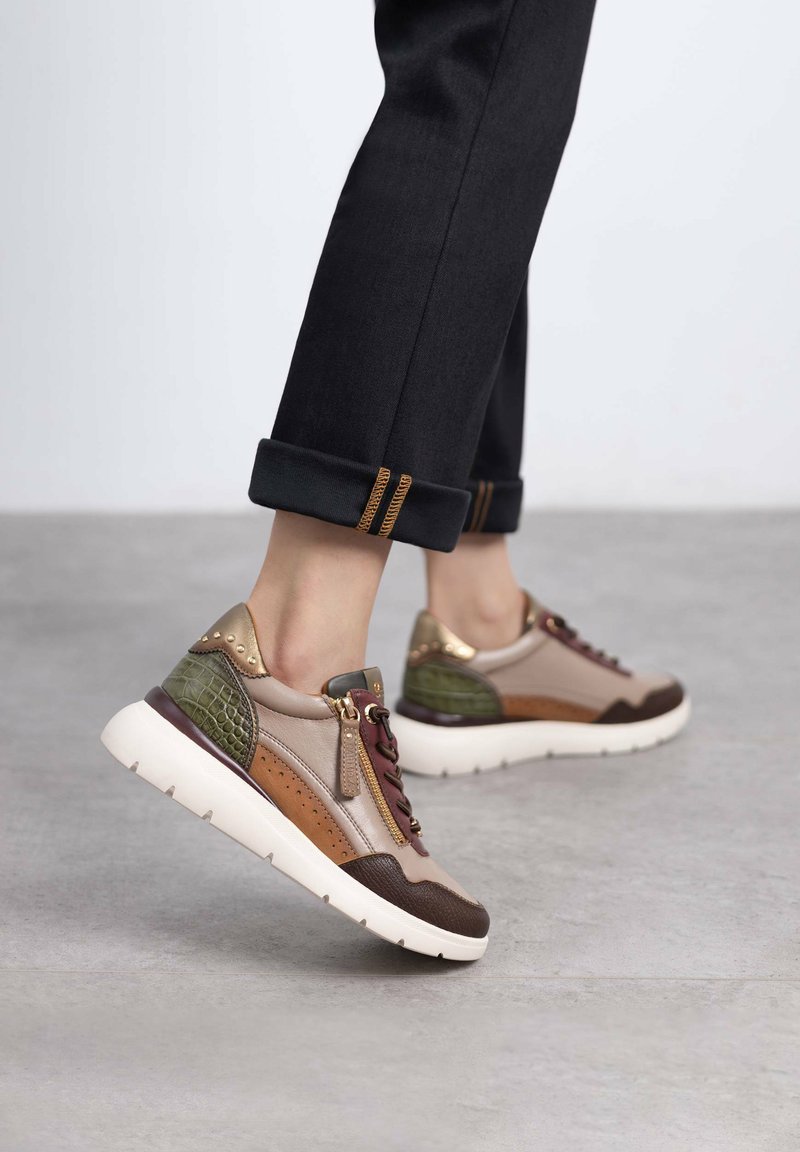 Sneaker multicolore con una combinazione di pelle beige, marrone e verde, caratterizzata da un design testurizzato, dettagli dorati e una suola chunky bianca.