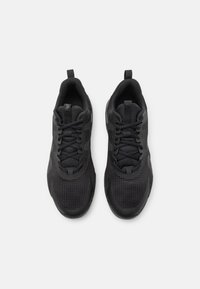 Zapatillas deportivas negras con parte superior de malla, cuello acolchado y cordones planos. Presentan acentos texturizados y una lengüeta en el talón.