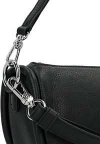 Zwarte leren tas met gestructureerd oppervlak, voorzien van een zilveren sluiting en een afneembare schouderband. Close-up van het bevestigingsdetail.